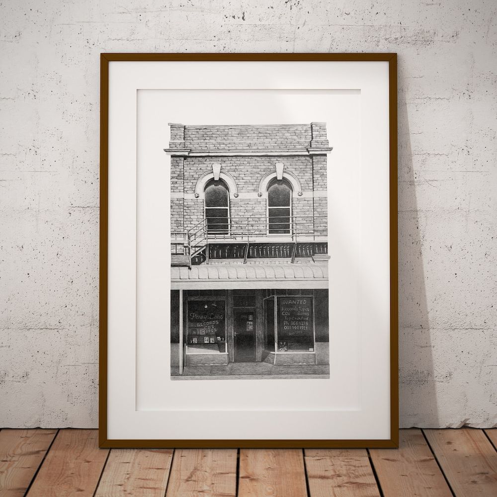 The Penny Lane print in a slim wooden frame with a white mount, leaning against a concrete wall